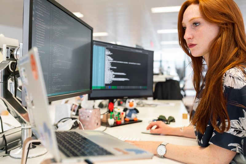 Software developer focused on code across two monitors at her desk