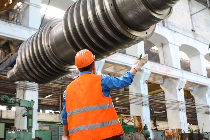 Skilled tradesperson in a hard hat and hi-vis vest working on the factory floor